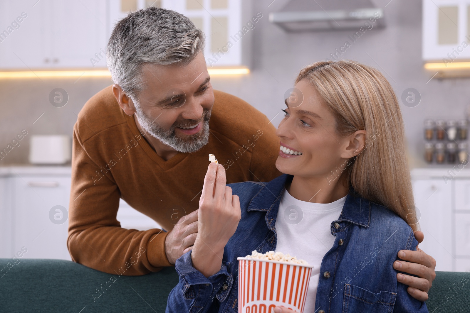 Photo of Happy affectionate couple with popcorn spending time together on sofa at home. Romantic date