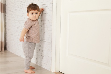 Photo of Cute baby holding on to wall at home.  Learning to walk