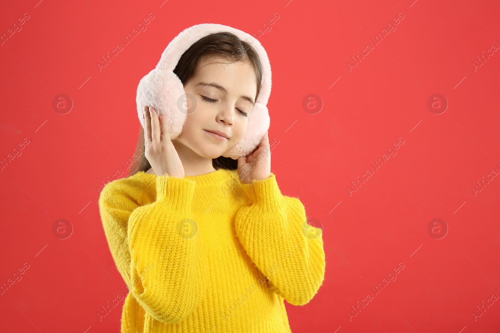 Photo of Cute girl wearing stylish earmuffs on red background. Space for text