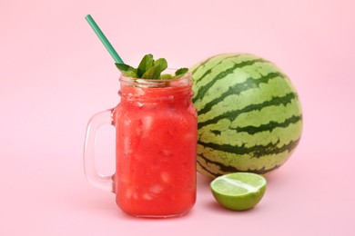 Glass of delicious watermelon drink with mint and fresh fruits on pink background