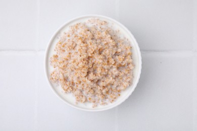 Photo of Tasty wheat porridge with milk in bowl on white table, top view