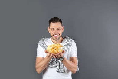 Man with bowl of potato chips on grey background