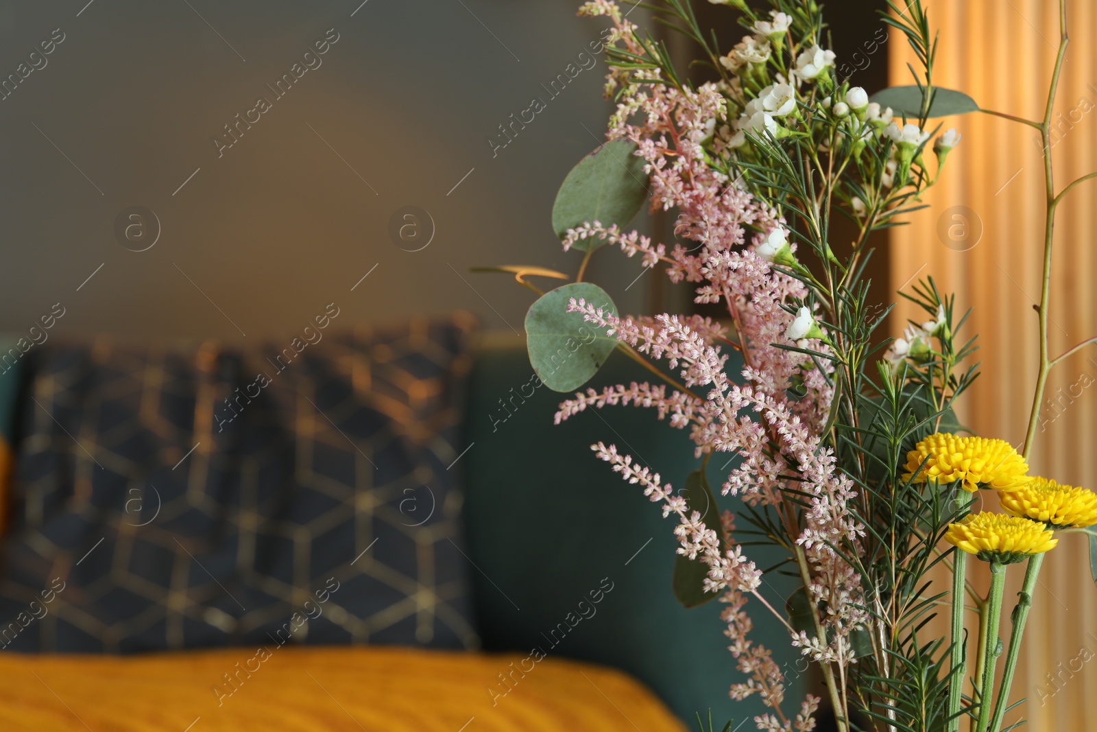 Photo of Beautiful flowers and green branches indoors, space for text