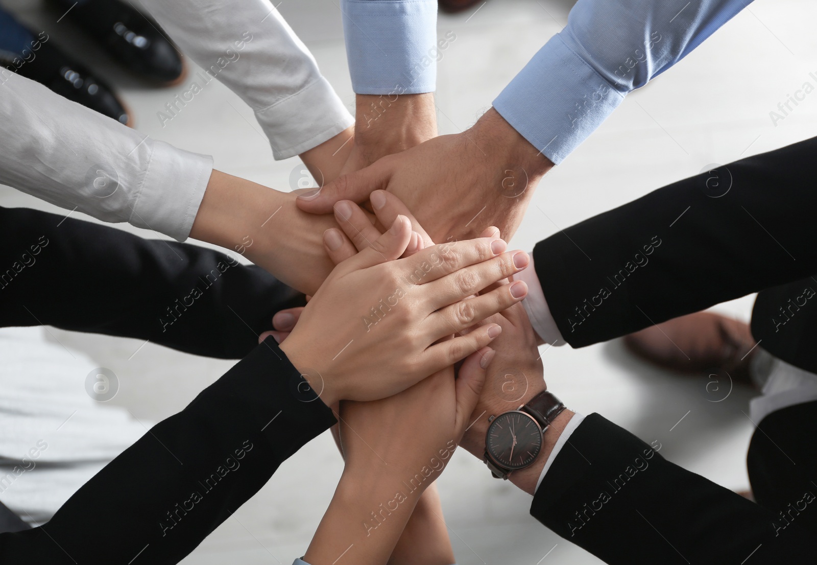People holding hands together over light background, top view. Unity concept Photo of People holding hands together over light background, top view. Unity concept