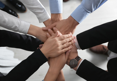 Photo of People holding hands together over light background, top view. Unity concept