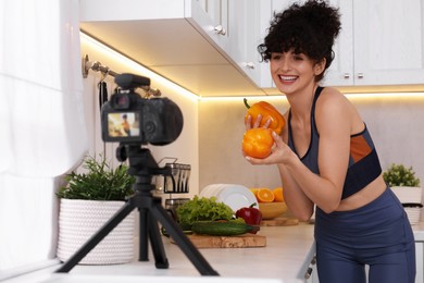 Photo of Smiling food blogger explaining something while recording video in kitchen