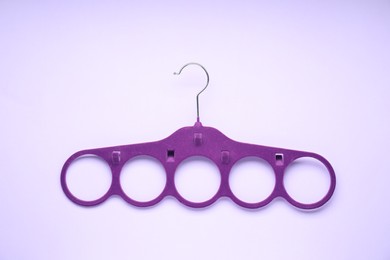 Photo of Empty purple scarf hanger on lilac background, top view