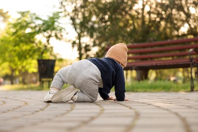 Photo of Learning to walk. Little baby crawling in park, back view