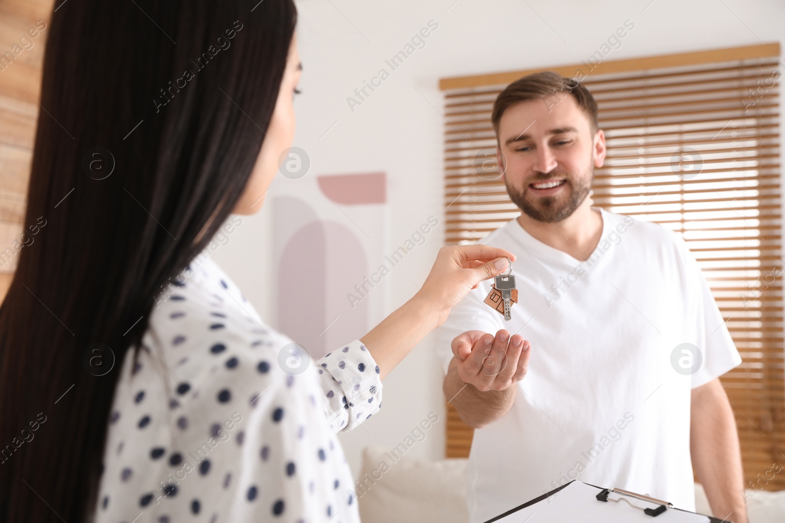Photo of Real estate agent giving key to happy young man in new house, focus on hands