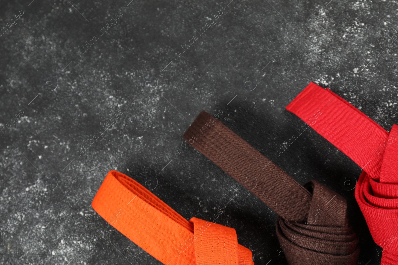 Photo of Colorful karate belts on gray background, flat lay. Space for text