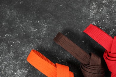 Colorful karate belts on gray background, flat lay. Space for text