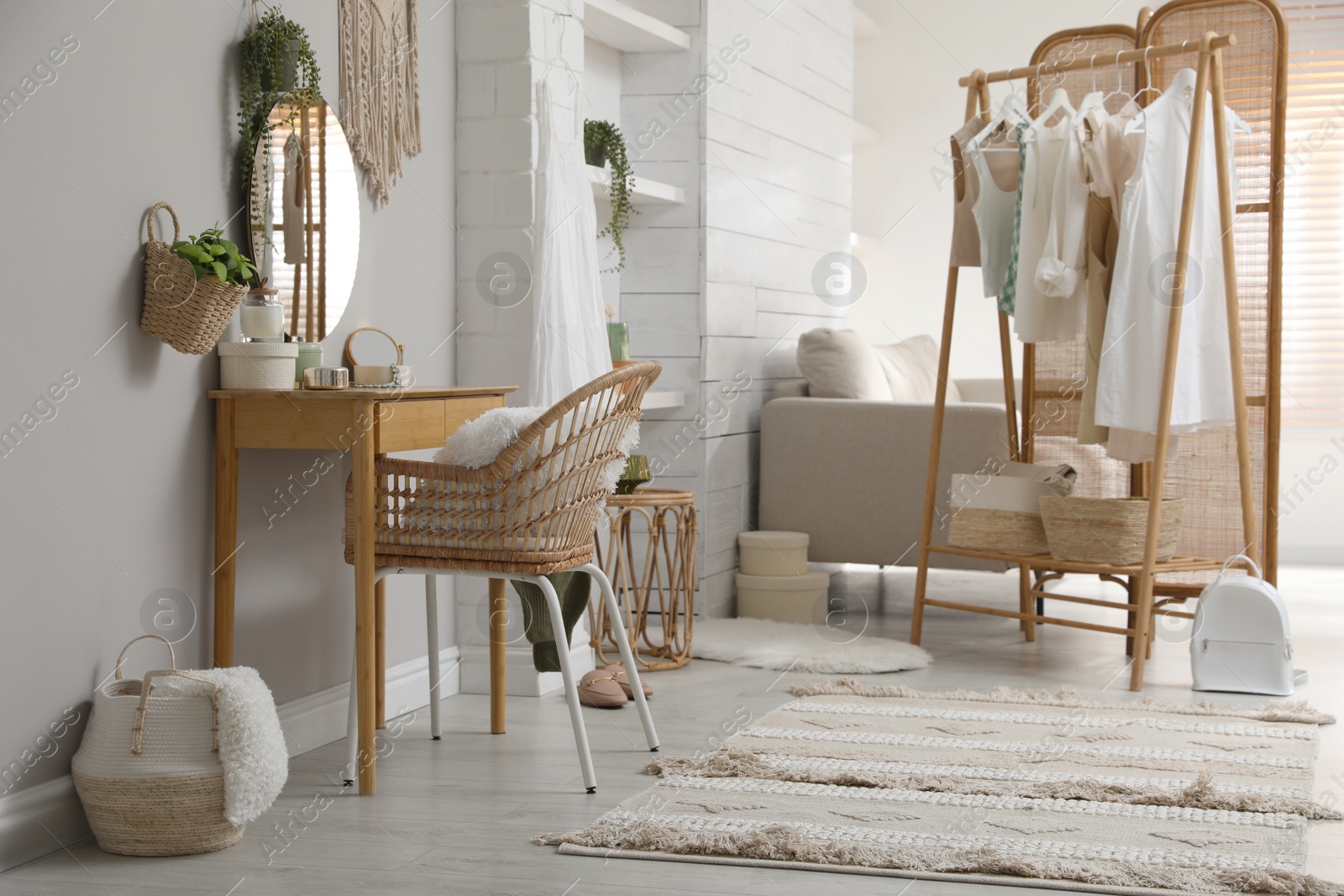 Photo of Rack with stylish women's clothes and dressing table in room. Interior design