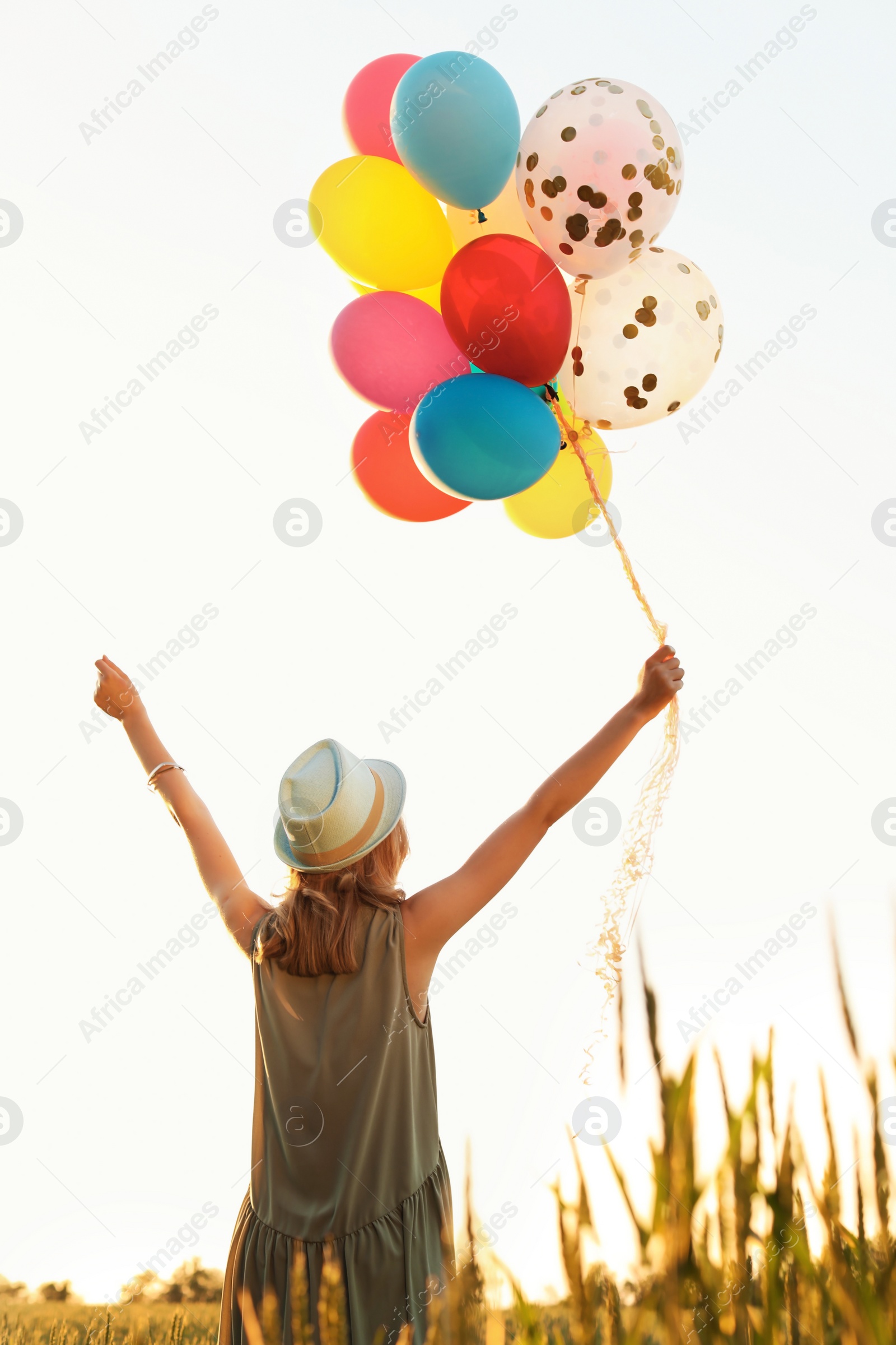 Photo of Young woman with colorful balloons outdoors on sunny day