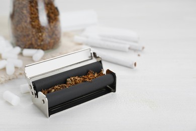 Photo of Roller with tobacco on white wooden table, space for text. Making hand rolled cigarettes