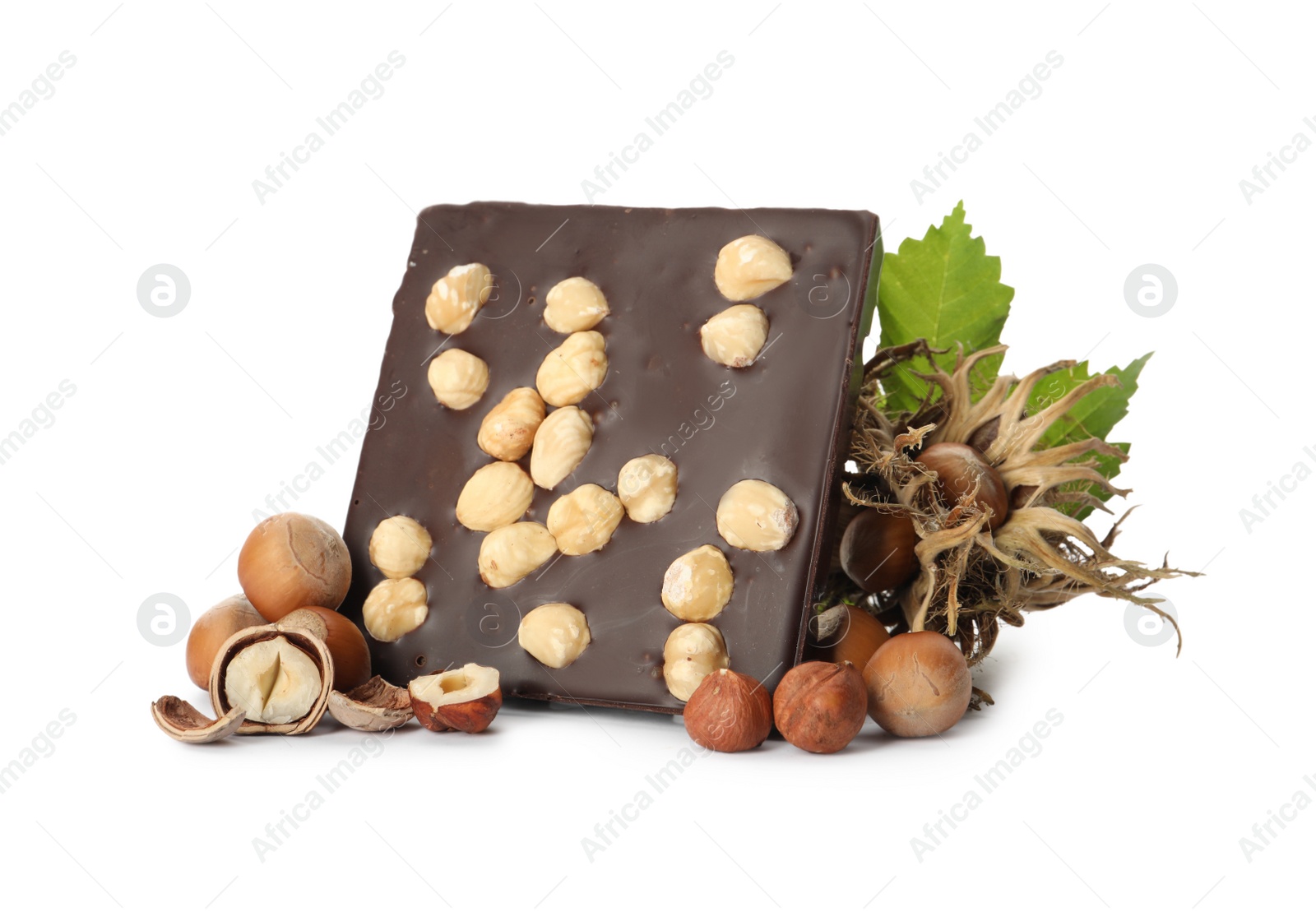 Photo of Delicious chocolate bar with hazelnuts and green leaves on white background