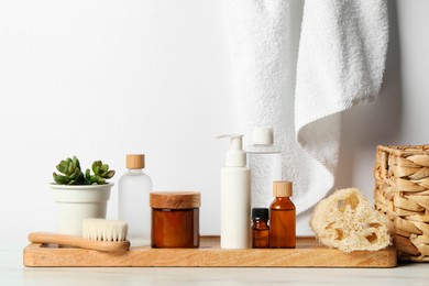 Different bath accessories and personal care products on light table near white wall