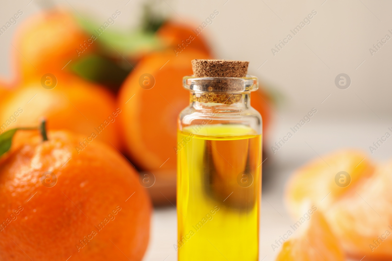 Photo of Bottle of tangerine essential oil on blurred background, closeup