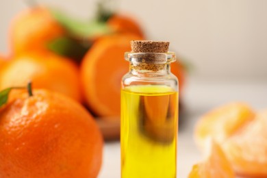 Photo of Bottle of tangerine essential oil on blurred background, closeup