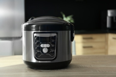 Photo of Modern multi cooker on wooden table in kitchen