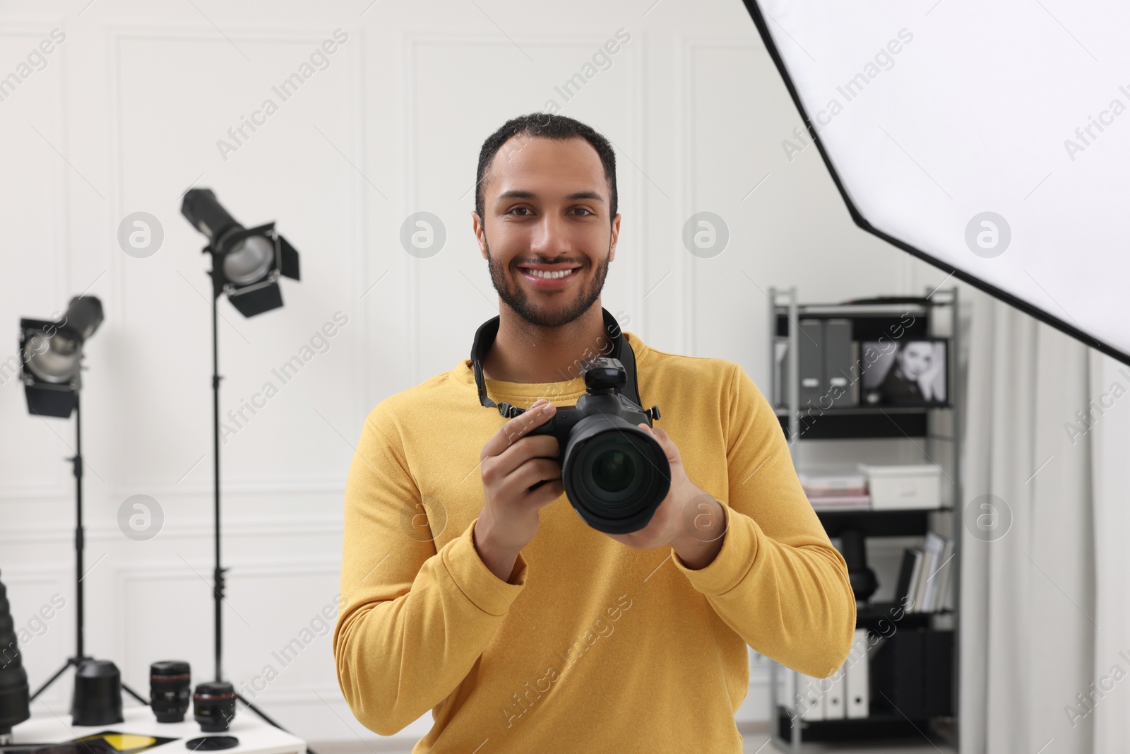 Photo of Young professional photographer with camera in modern photo studio