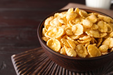 Bowl of tasty crispy corn flakes on wooden board, closeup