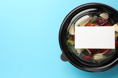 Photo of Tasty food in container on light blue background, top view. Space for text