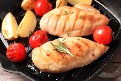 Photo of Grill pan with fried chicken breast and garnish, closeup