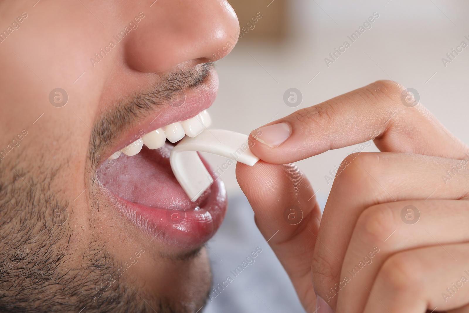 Photo of Man with chewing gum on blurred background, closeup