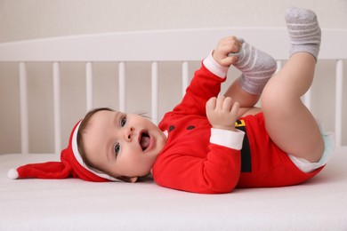 Photo of Cute baby wearing festive Christmas costume lying in crib