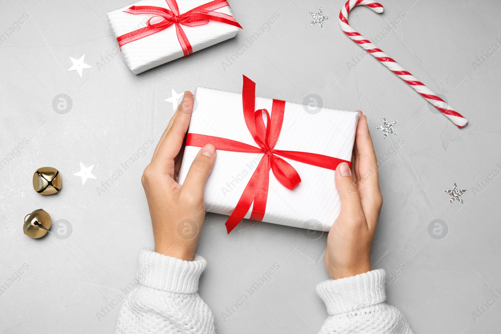 Photo of Young woman holding Christmas gift on grey stone background, flat lay