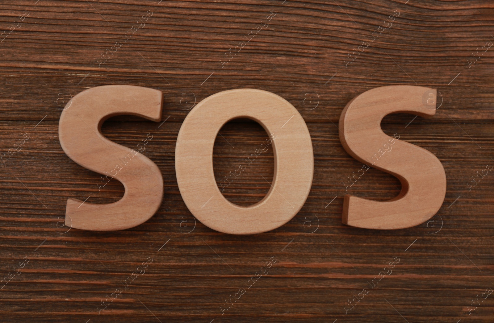 Photo of Abbreviation SOS made of letters on wooden table, top view