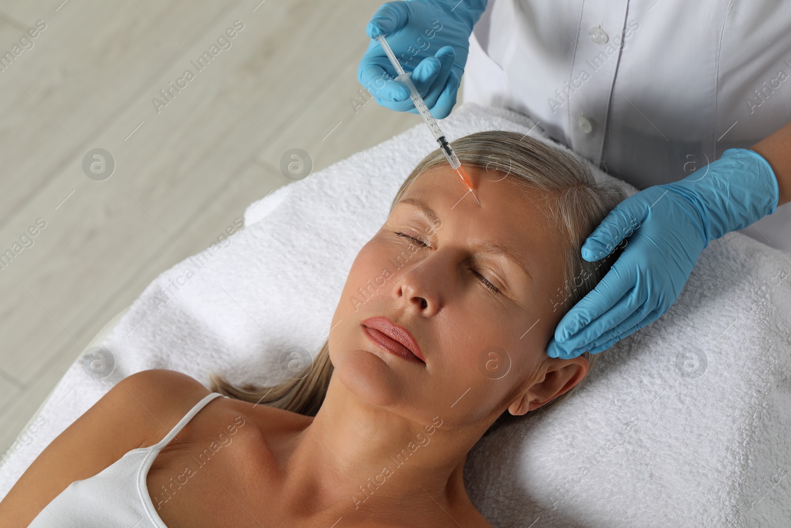 Photo of Doctor giving facial injection to senior woman in clinic. Cosmetic surgery