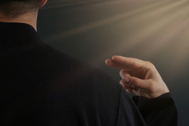 Image of Holy light and priest making cross sign on black background, closeup