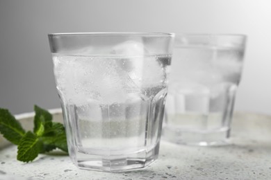 Photo of Glasses of soda water with ice and mint on marble tray, closeup. Space for text