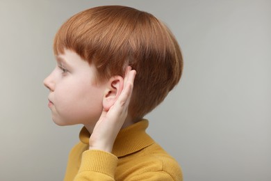 Photo of Little boy with hearing problem on grey background, space for text
