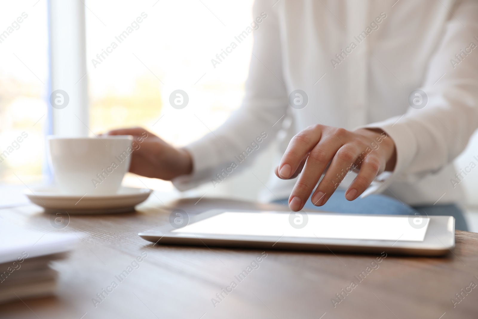 Photo of Businesswoman working with modern tablet at wooden table in office, closeup