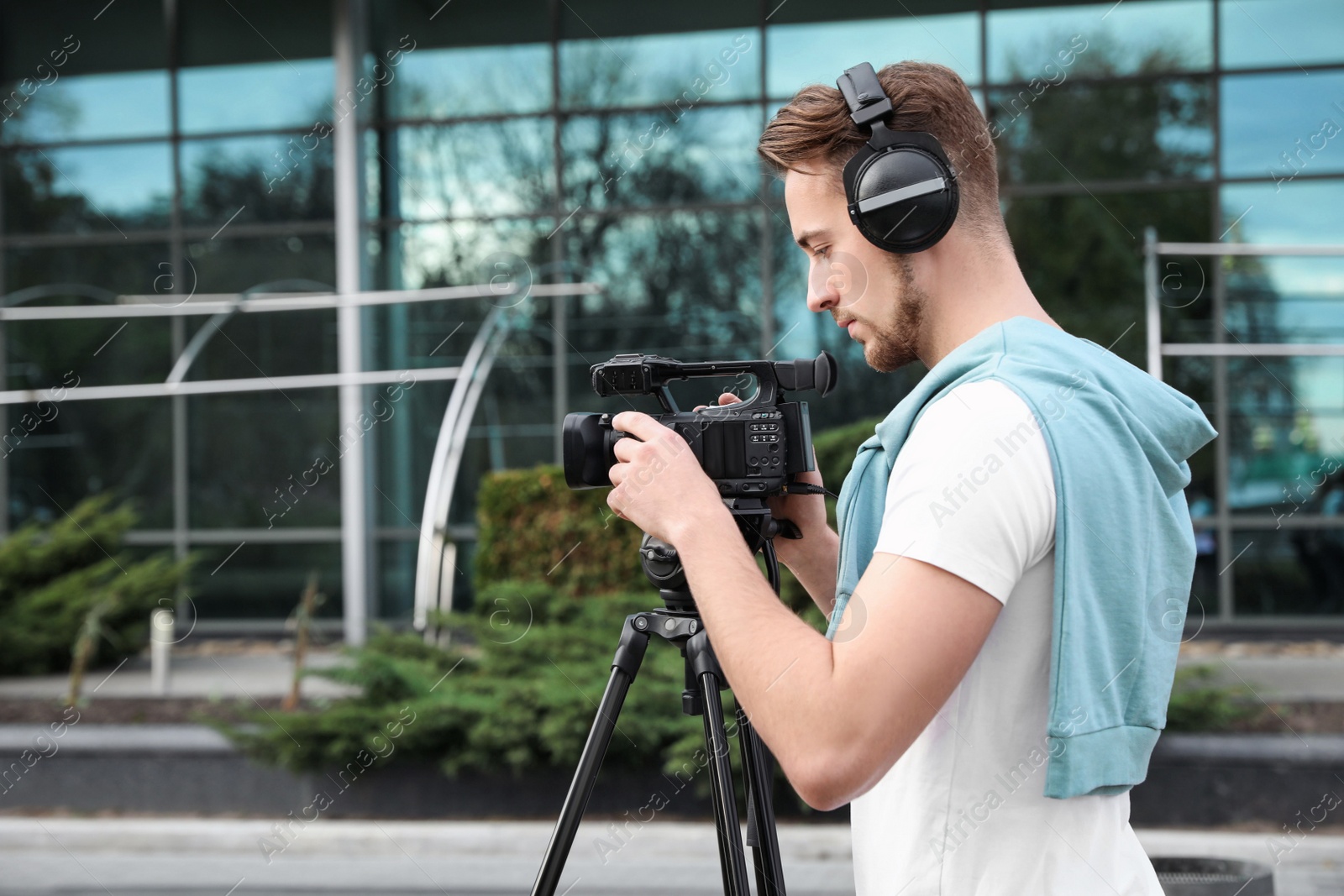 Photo of Video operator with camera working on city street. Space for text