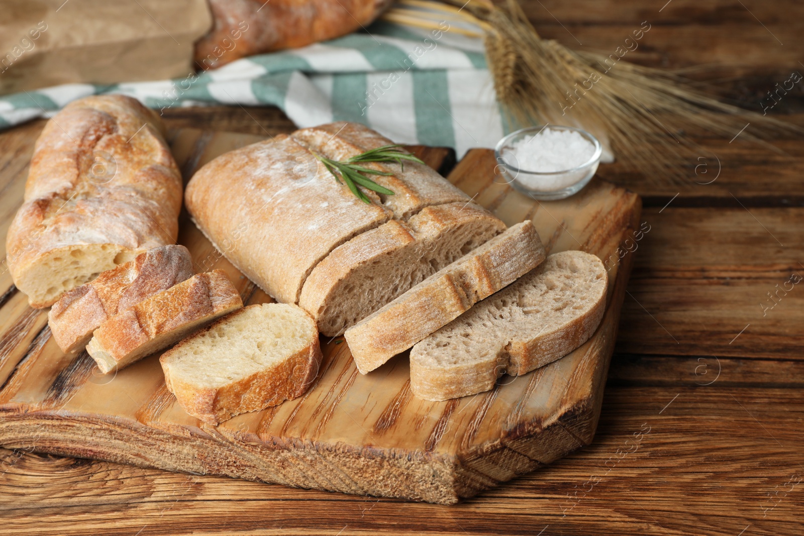Photo of Crispy fresh ciabatta and baguette on wooden table