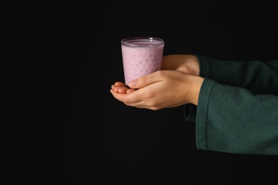 Woman holding fig smoothie on black background, closeup