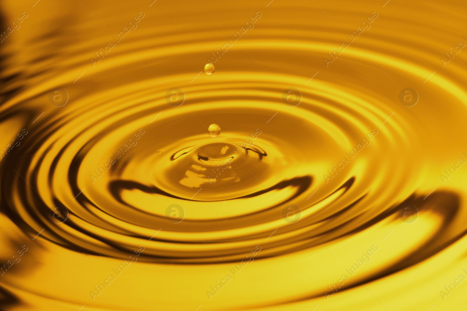 Image of Splash of golden oily liquid with drops as background, closeup