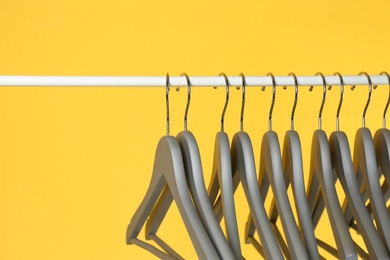 Metal rack with clothes hangers on color background, closeup. Space for text