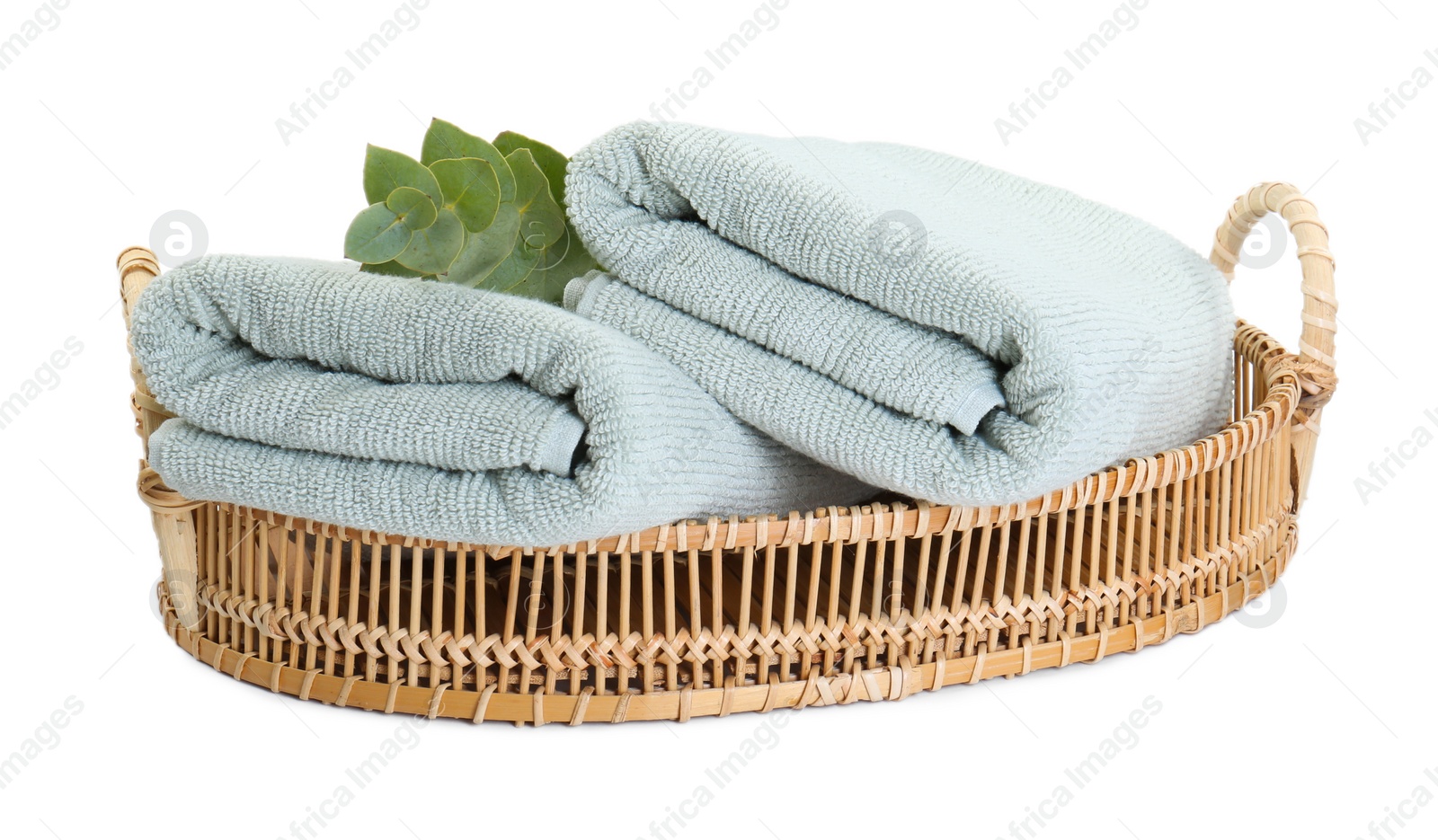 Photo of Basket with soft towels and eucalyptus branch isolated on white