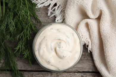 Photo of Tasty creamy sauce and fresh dill on wooden table, flat lay