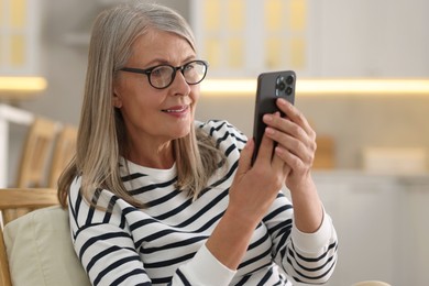 Photo of Senior woman using mobile phone at home
