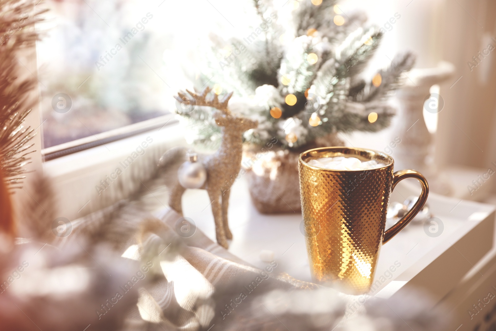 Photo of Golden cup of cocoa and Christmas decor on window sill indoors