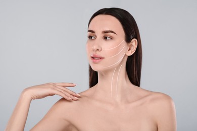 Image of Attractive woman with perfect skin after cosmetic treatment on grey background. Lifting arrows on her face