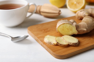 Photo of Wooden board with cut ginger on table. Cough remedies