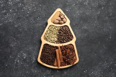 Different spices and nuts on dark gray textured table, top view