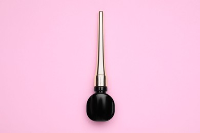 Photo of Black eyeliner on pink background, top view. Makeup product