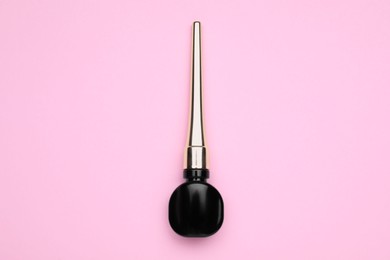 Black eyeliner on pink background, top view. Makeup product